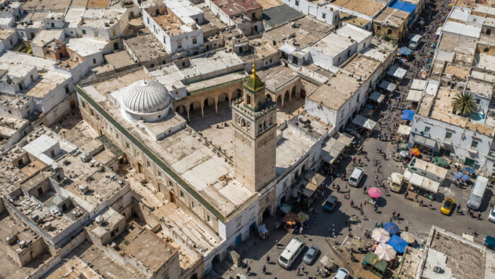 Sustainable Tourism in North Africa: The DCCI Framework and the Mediterranean Investment Corridor — Part I 1 Aerial view of a traditional North African medina and historic mosque, illustrating heritage tourism integration and local urban economies within the Mediterranean corridor. sustainable tourism in north africa.